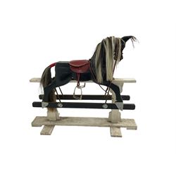 20th century black painted rocking horse on white painted trestle base, fitted with saddle and stirrups 
