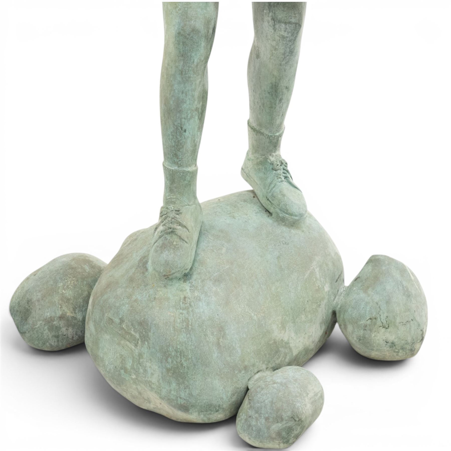 After Eneri Prosperi, bronze garden child statues, depicting children balancing on rock-form bases, the boy in shirt and shorts, the girl in dress with raised arms, surrounded by loose rounded pebble elements