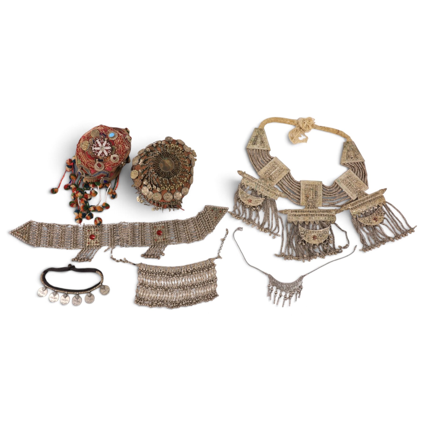 Collection of Middle Eastern jewellery, including silver necklace with a crescent  shaped pendent with beadwork and barrel tasselled ends, nickel silver wedding necklace with filigree decoration, coin bracelet, two bridal wedding caps and two others 