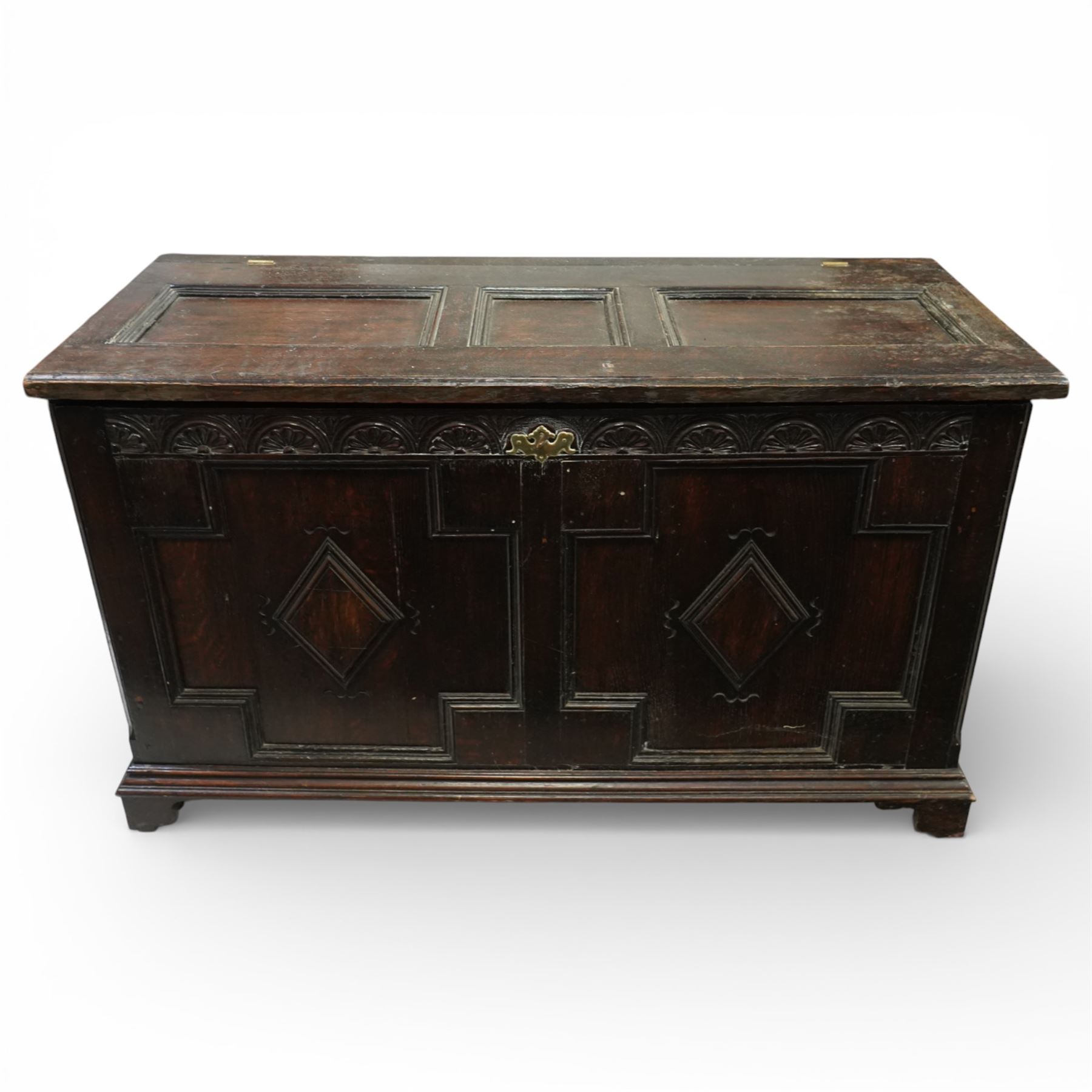 18th century oak coffer, the three panel hinged lid above a frieze carved with repeated lunettes, the front formed with geometric moulded panels centred by lozenge motifs, raised on bracket feet