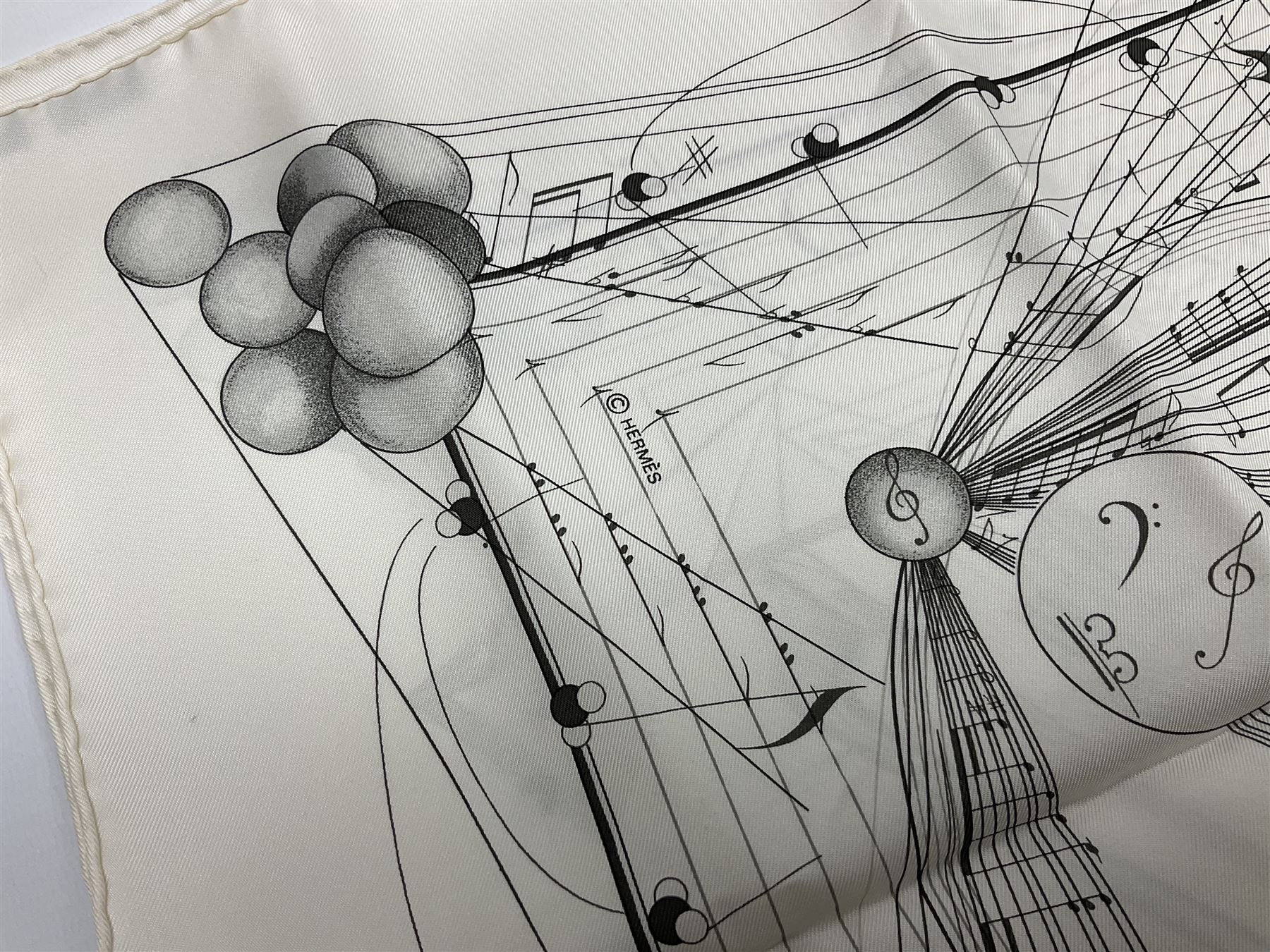 Hermès 'La Musique Des Spheres' silk scarf, designed by Zoe Pauwels in 1996, printed with a Viola Medici surrounded by musical motifs in black, on ivory white ground, with rolled hand stitched edges and Hermes material label, 87cm square