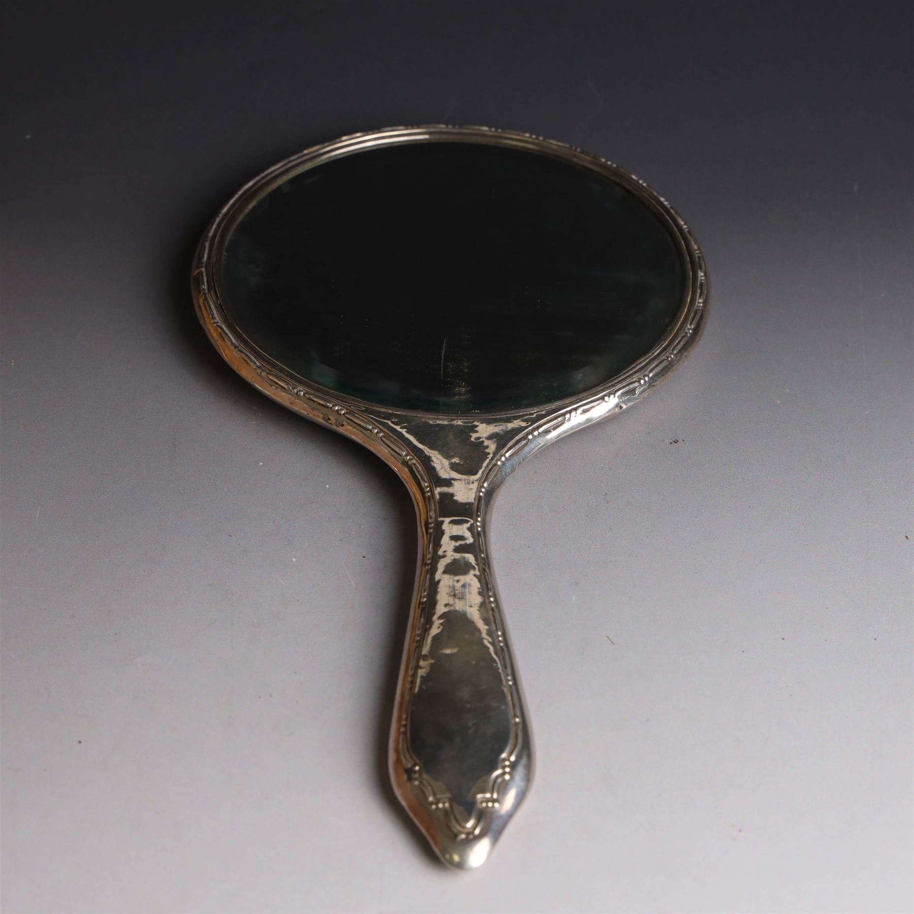 Five silver mounted dressing table items, including 1920s mirror and hairbrush set, with engraved initial to reverse, pair of clothes brushes with engraved initials and engine turned decoration and an oval clothes brush, all hallmarked 