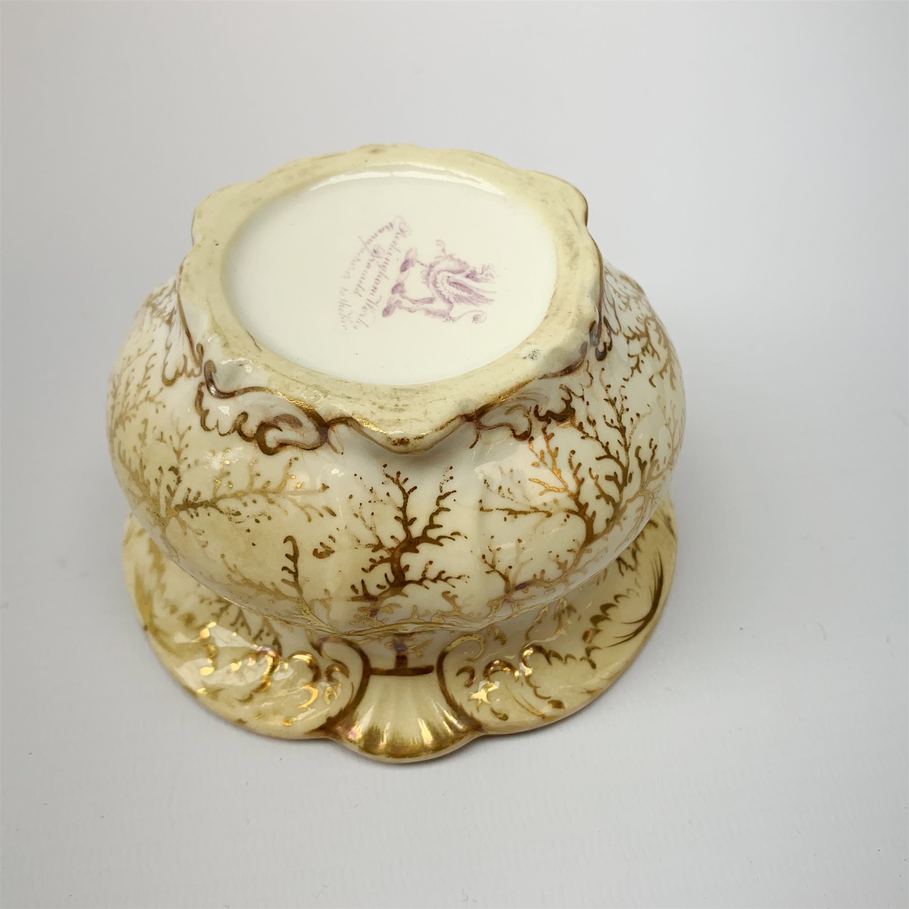 A Rockingham inkwell, with scroll rim, the whole decorated in gilt with a seaweed pattern, with a printed puce mark beneath, D9.5cm. 