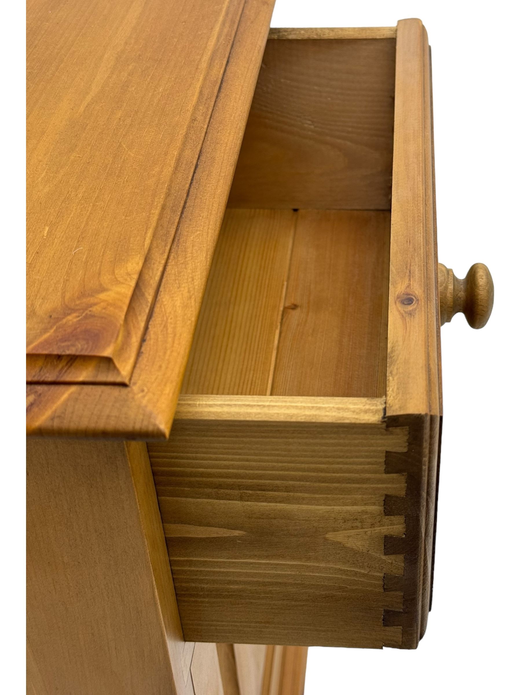 Pine chest of drawers topped with carved pediment with acorn and oak leaf motif, fitted with two short over three long drawers, standing on shaped apron base (W92, D46, H97cm); pine bedside cabinet, single drawer above paneled cupboard door enclosing open storage, shaped plinth base (W43, L32, H67cm)