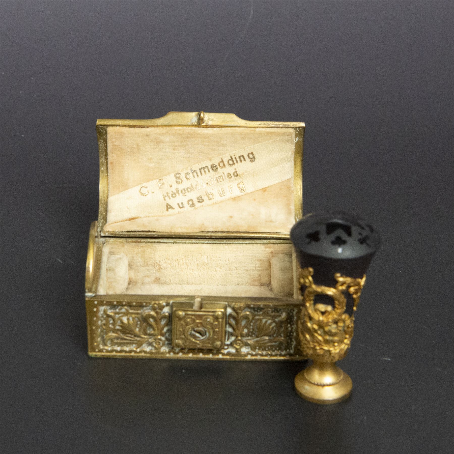 Gilt bronze mounted black glass seal, contained within a brass casket, with velvet interior and inner label reading 'C. F. Schmedding Augsburg', together with a porcelain handled seal decorated with floral sprays on a pink ground