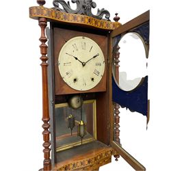 A late 19th century spring driven American Eight-day wall clock, striking the hours on a bell, in a parquetry case with contrasting oak, maple, walnut, and other hardwoods, with a flat top, carved cresting and finials rectangular glazed door flanked by finely turned pilasters, with a painted dial with roman numerals and minute track, steel spade hands and faux mercury pendulum reflected in a rear case mirror.   


