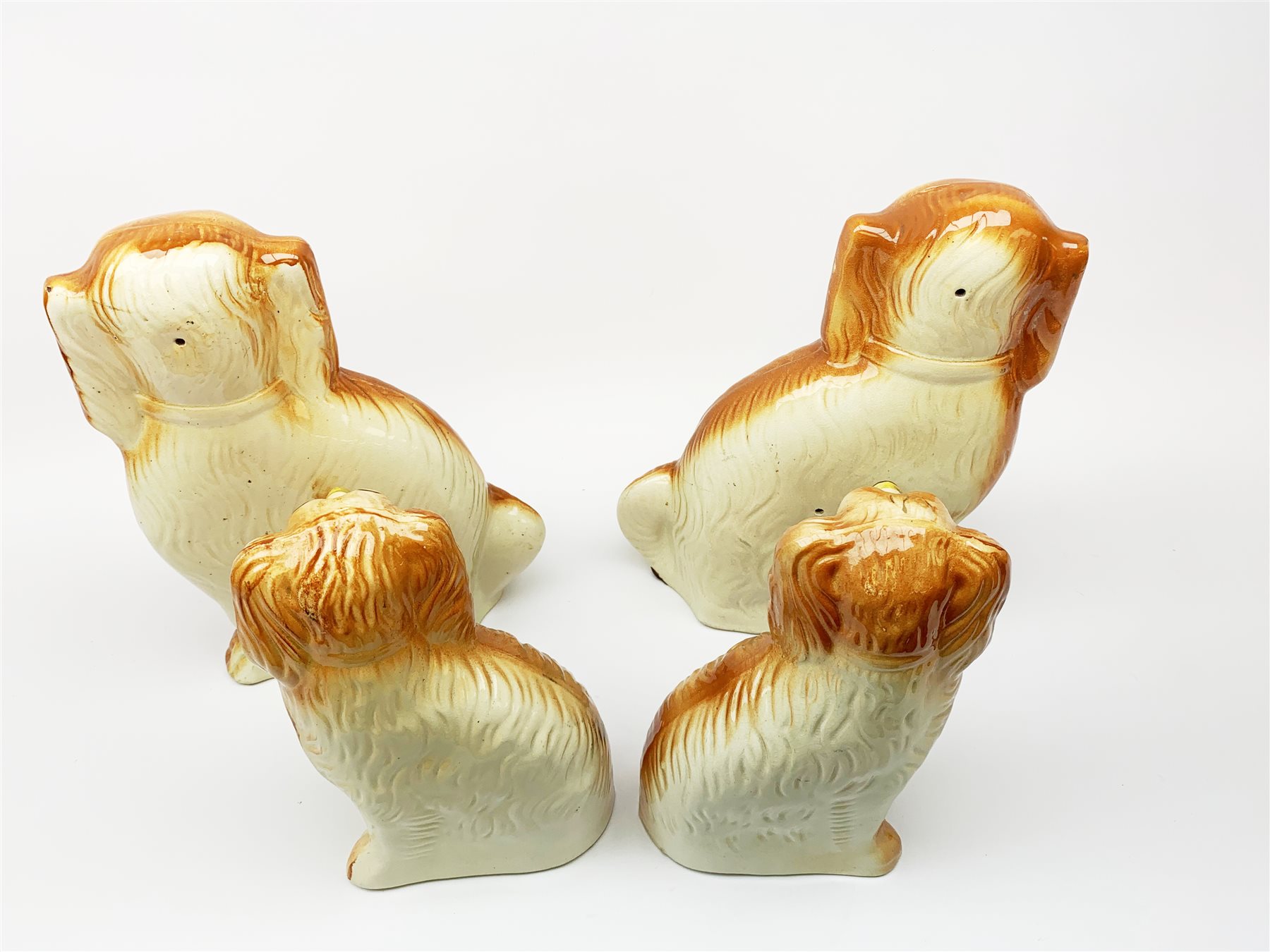 A pair of large 19th century Staffordshire dogs with glass eyes, H34cm, together with another smaller pair with glass eyes, H26.5cm, each in the form of a spaniel with russet coat. (4). 