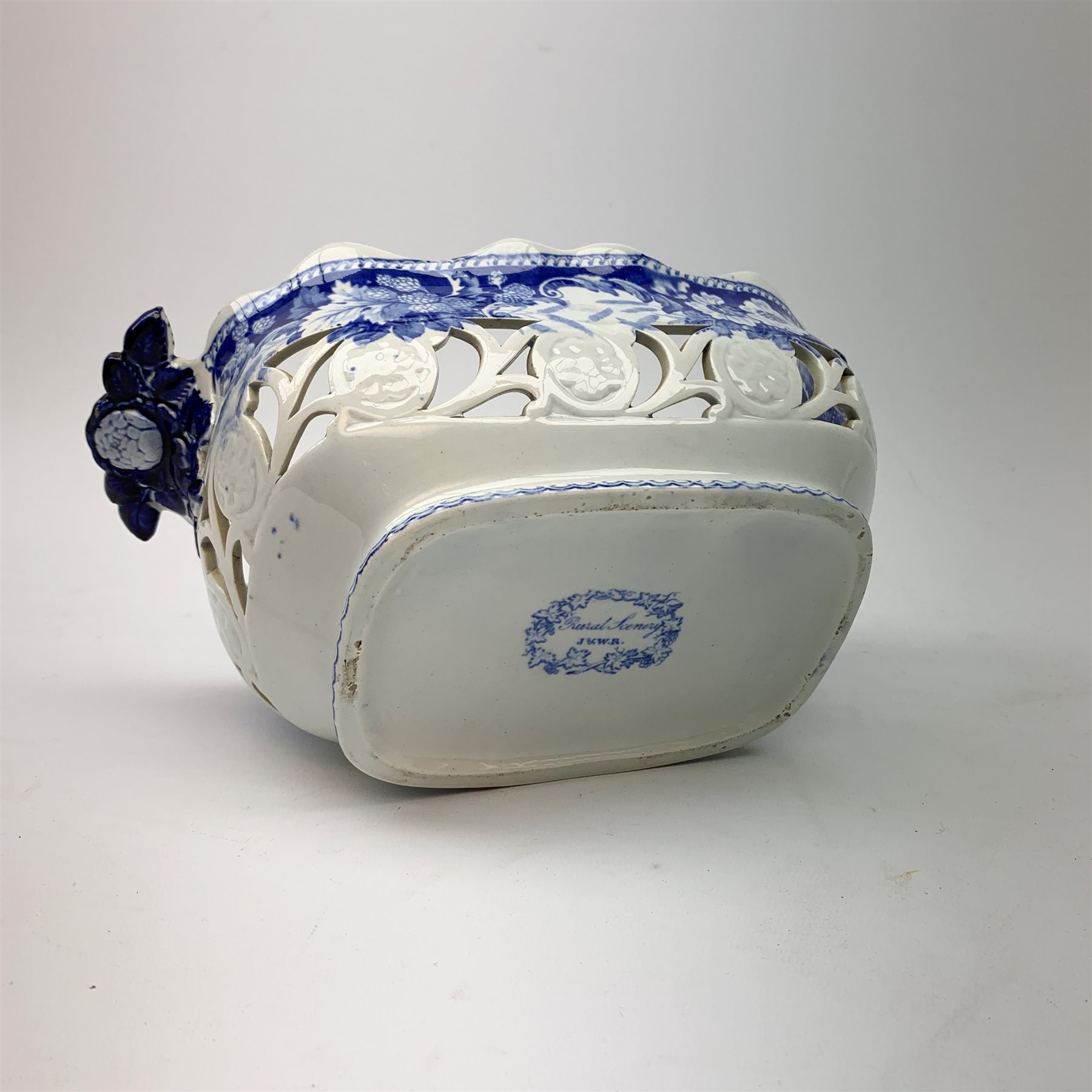 Mid 19th century blue and white transfer printed pearlware reticulated chestnut basket, of oval form with twin handles, decorated to the interior with figures before a classical temple within a garden setting, including handles W26cm, together with a mid 19th century blue and white transfer printed pearlware stand with reticulated edge, decorated with a Willow Pattern, L25cm, and a John and William Ridgeway blue and white transfer printed twin handled pierced basket, decorated with a pastoral scene containing figures at work, with printed mark beneath, including handles L25cm
