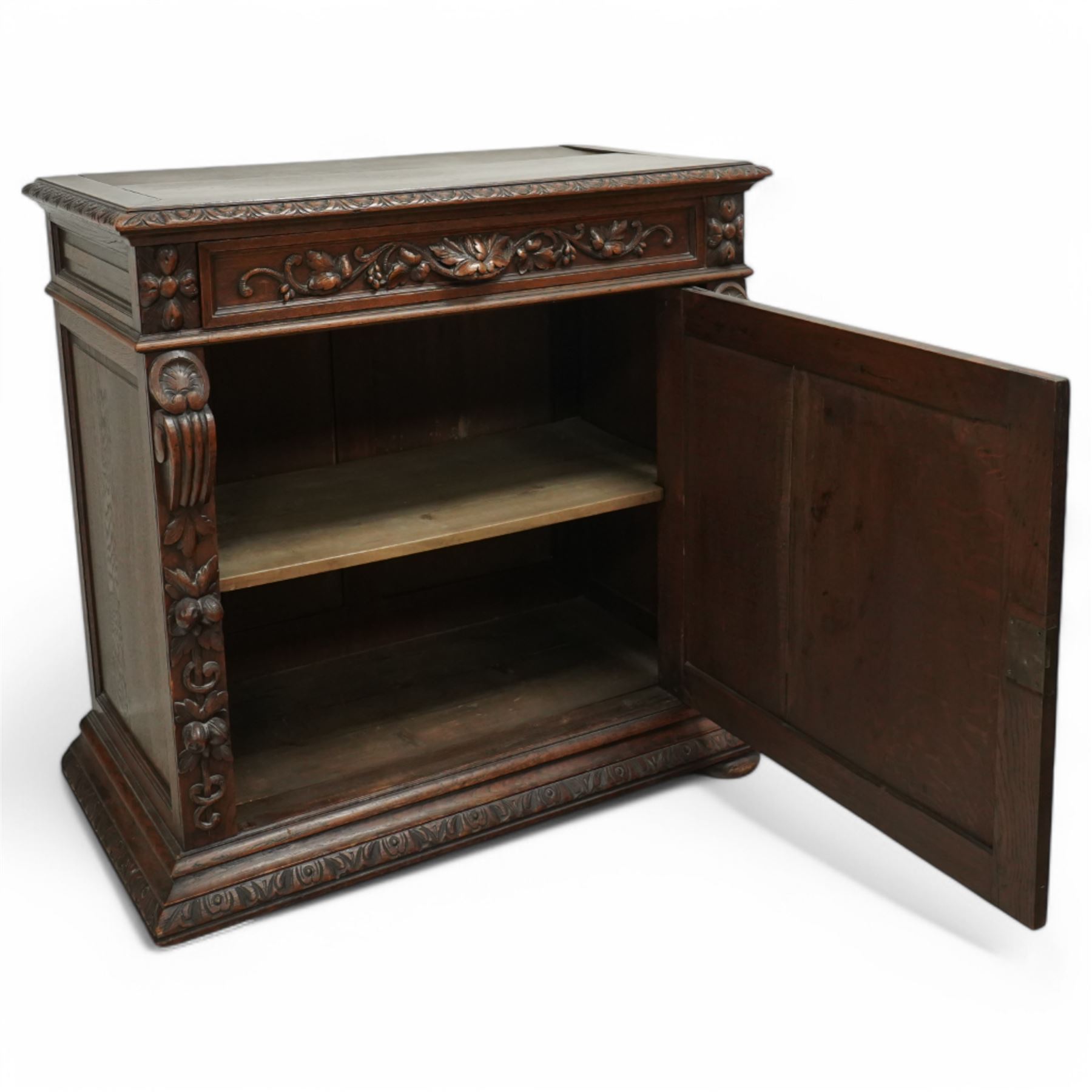 19th-century heavily carved oak baroque style cupboard with vine and floral carved frieze drawer above panelled cupboard door with floral carved appliqué (detached) flanked by symmetrically carved scroll and vine decorated sides, on bun feet 