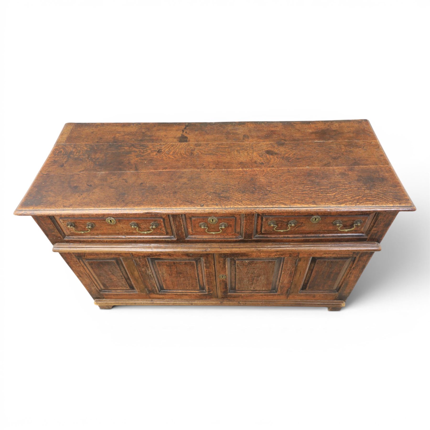 George III oak dresser base, rectangular top with moulded edge, three fielded panelled drawers with brass swan neck handles, over four fielded panelled front with the central two cupboard doors, raised on stile supports