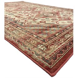 Persian design red ground rug, the field decorated with three interlinked lozenges and small stylised plant motifs, the multiple band border decorated with Boteh and floral motifs