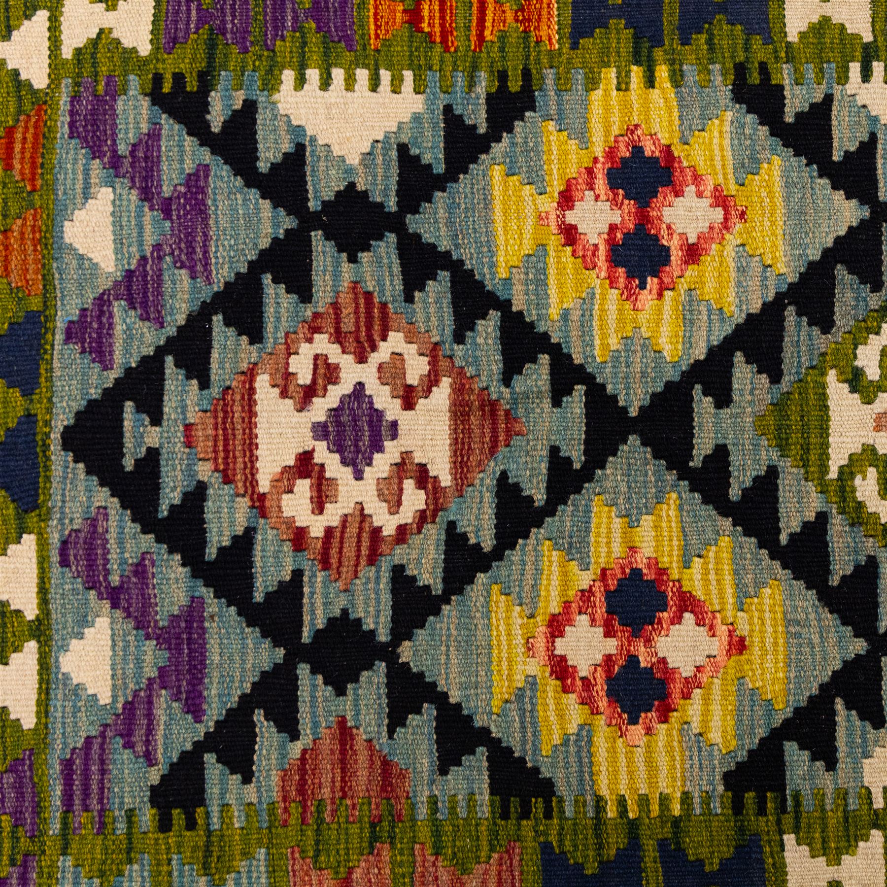 Afghan Maimana flatweave kilim, central field features large bold nested diamond motifs and stylized geometric lozenge patterns on olive purple, blue, and green tone ground, border stripe in blue tones, with fringe