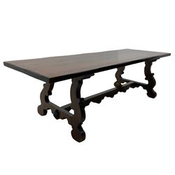 Large Spanish hardwood dining table, on shaped open ends supports joined by stretcher 
