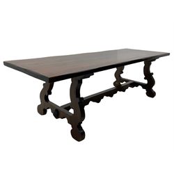 Large Spanish hardwood dining table, on shaped open ends supports joined by stretcher 
