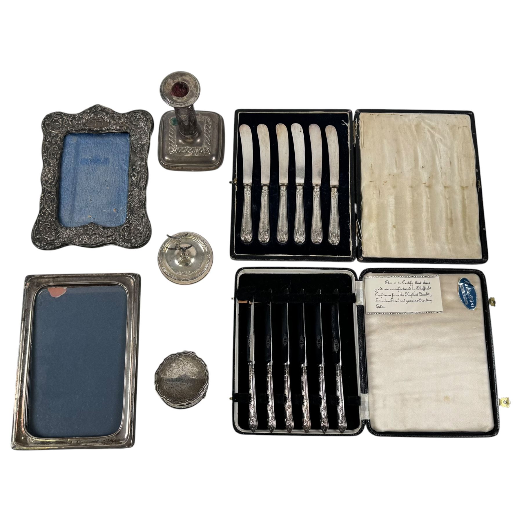 Two sets of cased silver handled tea knives, two silver mounted photo frames, silver mounted candlestick, silver ring holder with weighted base, silver mounted jewellery box