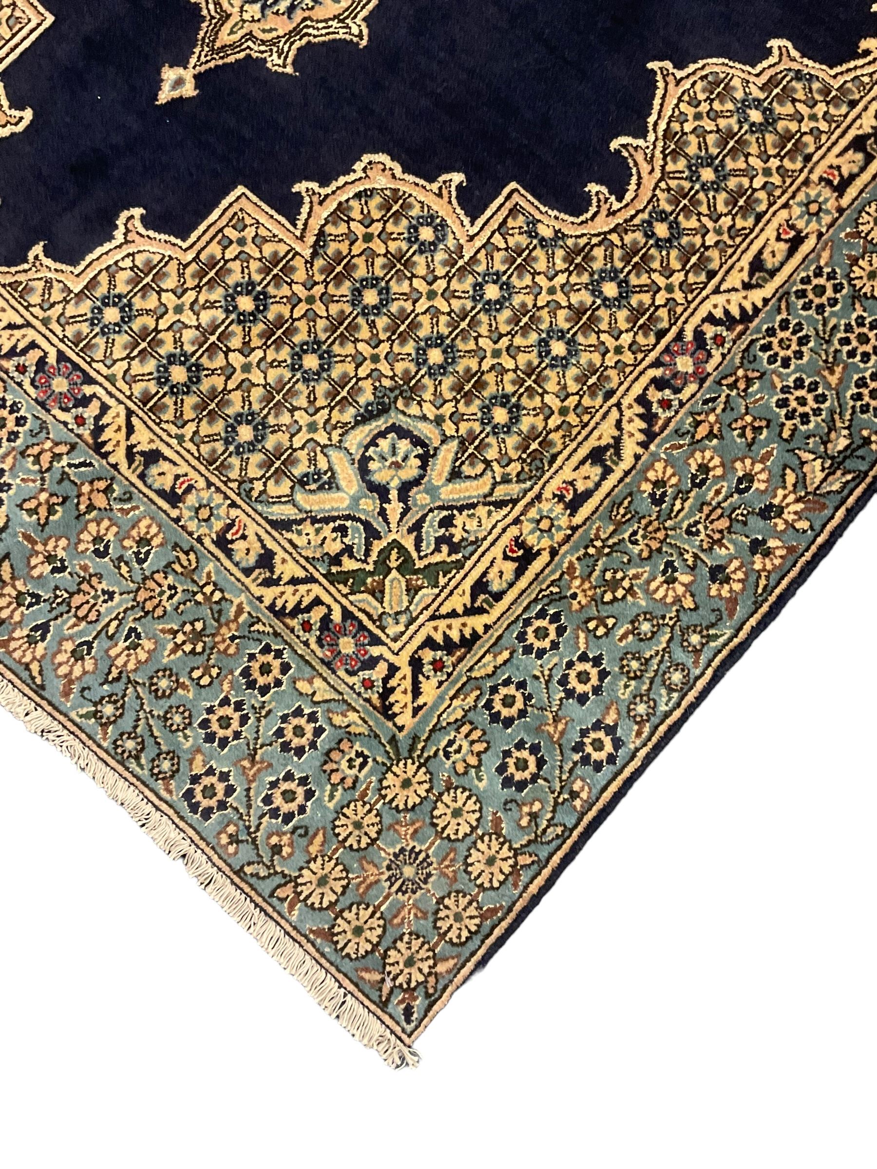 Central Persian Qum indigo ground rug with silk inlay, the plain field decorated with floral design medallion and lattice spandrels, the wide border decorated with trailing flowers and foliage 
