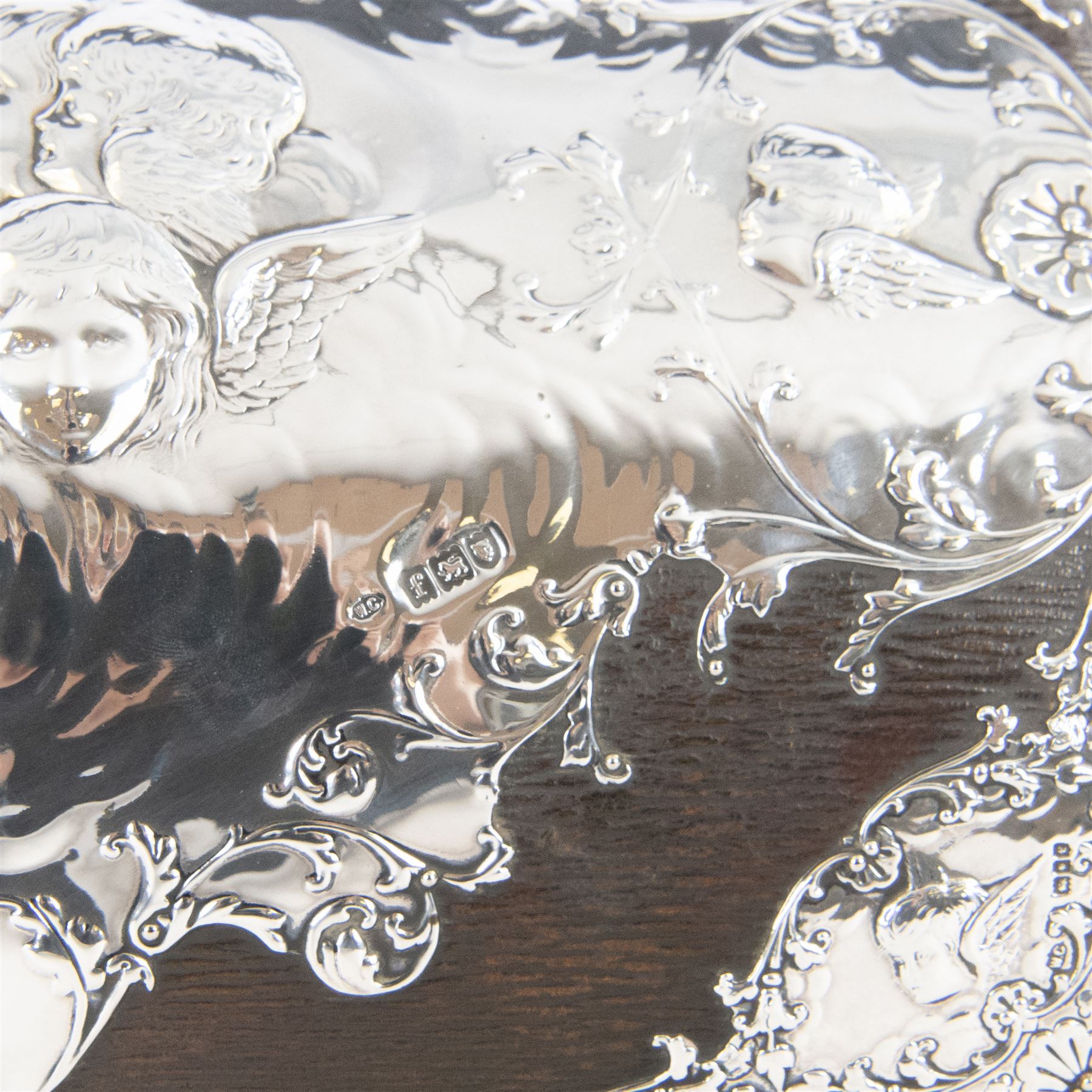 Edwardian silver mounted stationery box and silver mounted blotter, the box of rectangular form with curved front with applied repousse silver panels of putti within a scrolling foliate edge, the hinged cover opening to reveal an emerald green silk lined interior, the blotter with conforming silver mounted panels, each hallmarked William Comyns & Sons, London 1901, box H20cm W31cm D14cm, blotter H32cm W26.5cm