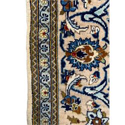 Persian Kashan ivory ground rug, the field decorated with stylised plant motifs and interlacing leafy branches, scrolling border decorated with further plant motifs, floral design guard bands  