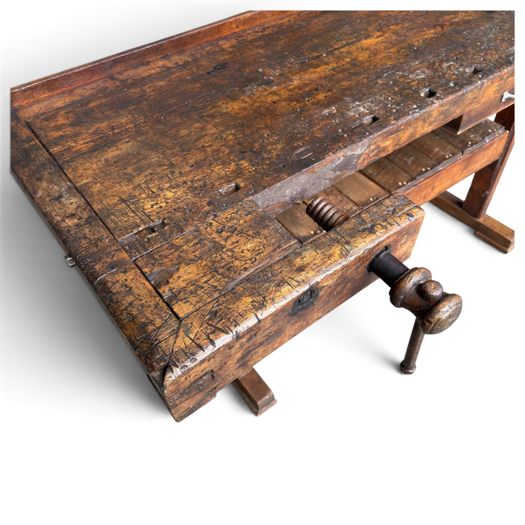 Large early 20th century rustic stained reclaimed pine workbench, the substantial plank top with recessed tool well and two homemade wooden screw vices, above a single frieze drawer and slatted undertier, raised on trestle end supports