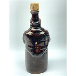 A treacle glazed stoneware bottle modelled as a man seated upon a barrel, not including cork stopper H24cm. 