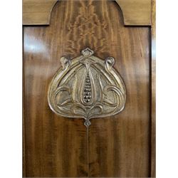 Edwardian mahogany triple wardrobe, central arched bevelled mirror flanked by two doors with carved Art Nouveau tulip motifs, enclosing shelves and hanging rails with drawers to base, on square tapering supports