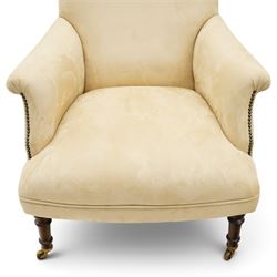 Sofas & Stuff - pair of ‘Thistle’ armchairs upholstered in neutral fabric, each with gently sloping back, padded scroll arms with close-set stud detailing, loose seat cushions, raised on turned wooden legs with brass castors
