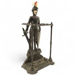 Early 20th century painted cast iron hall stand, formed as a standing armoured figure with red and yellow feathered crest, twin rails and integral drip tray with castellated edge