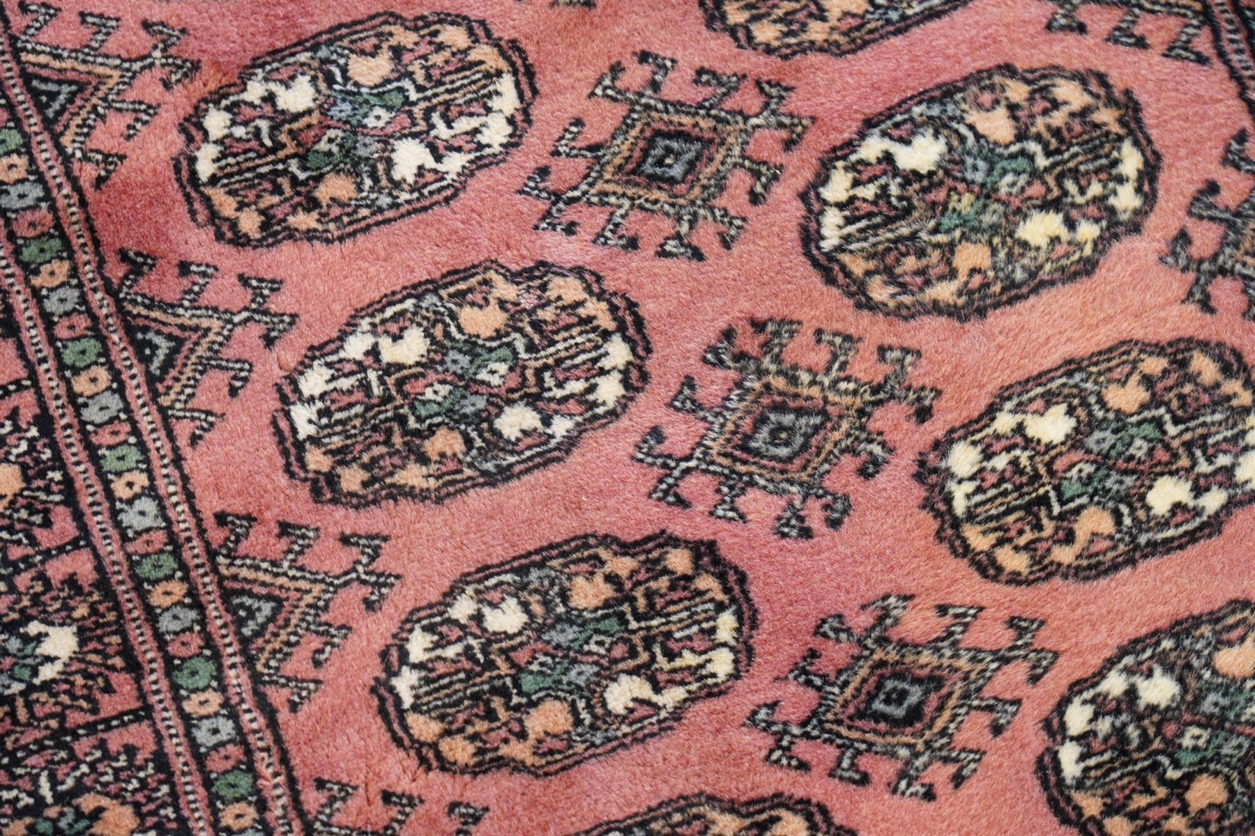 Afghan pale red ground runner, the field decorated with two rows of Gul motifs, within repeating patterned border