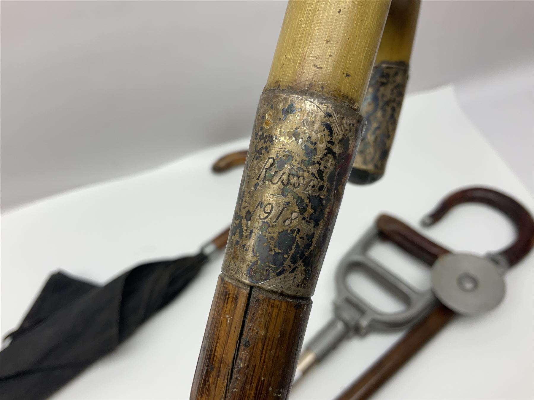 Early 20th century curved horn handle walking stick with hallmarked silver mounts, engraved L Russell 1918, together with a shooting stick by William Mills Birmingham, with leather handle, 'The Featherwaite' shooting stick and an umbrella with wooden handle