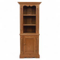 Contemporary stripped pine bookcase cabinet, the upper section with arched frieze and open shelving flanked by barley twist columns, over a single door cupboard base with matching twist supports and fielded panel door