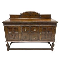 Early 20th century oak sideboard, raised stepped arch back over moulded rectangular top, fitted with two drawers and two panelled cupboards with geometric mouldings, on turned and lobe carved baluster feet united by stretchers 