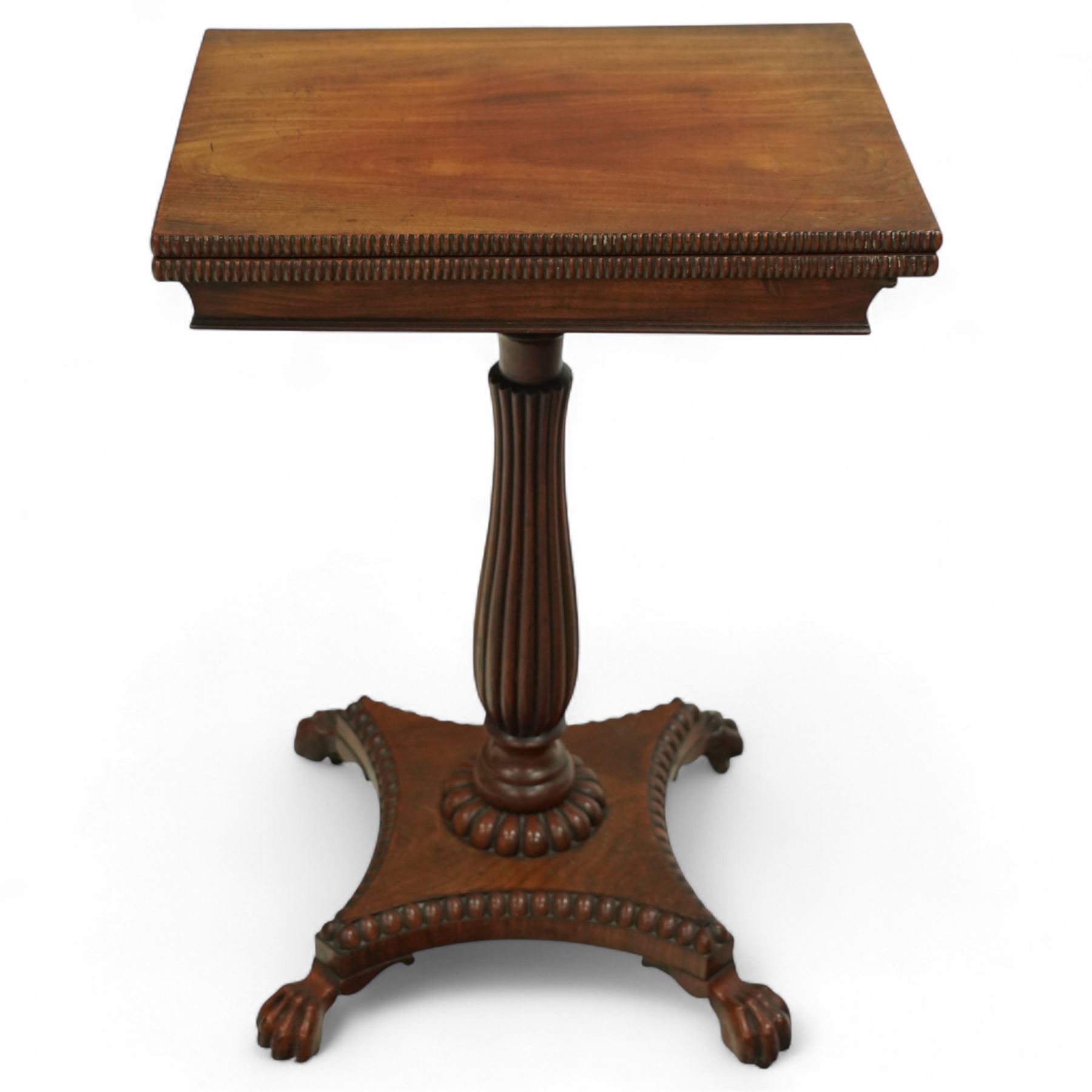William IV mahogany folding card table of unusually small proportions, rectangular swivel top with gadrooned edge, raised on a slender tapered reeded column over quatreform base with gadrooned border, terminating in carved lion paws feet