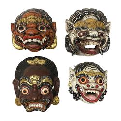 Four Balinese carved and painted wood dragon / demon masks, all with gilt decoration, largest L27cm