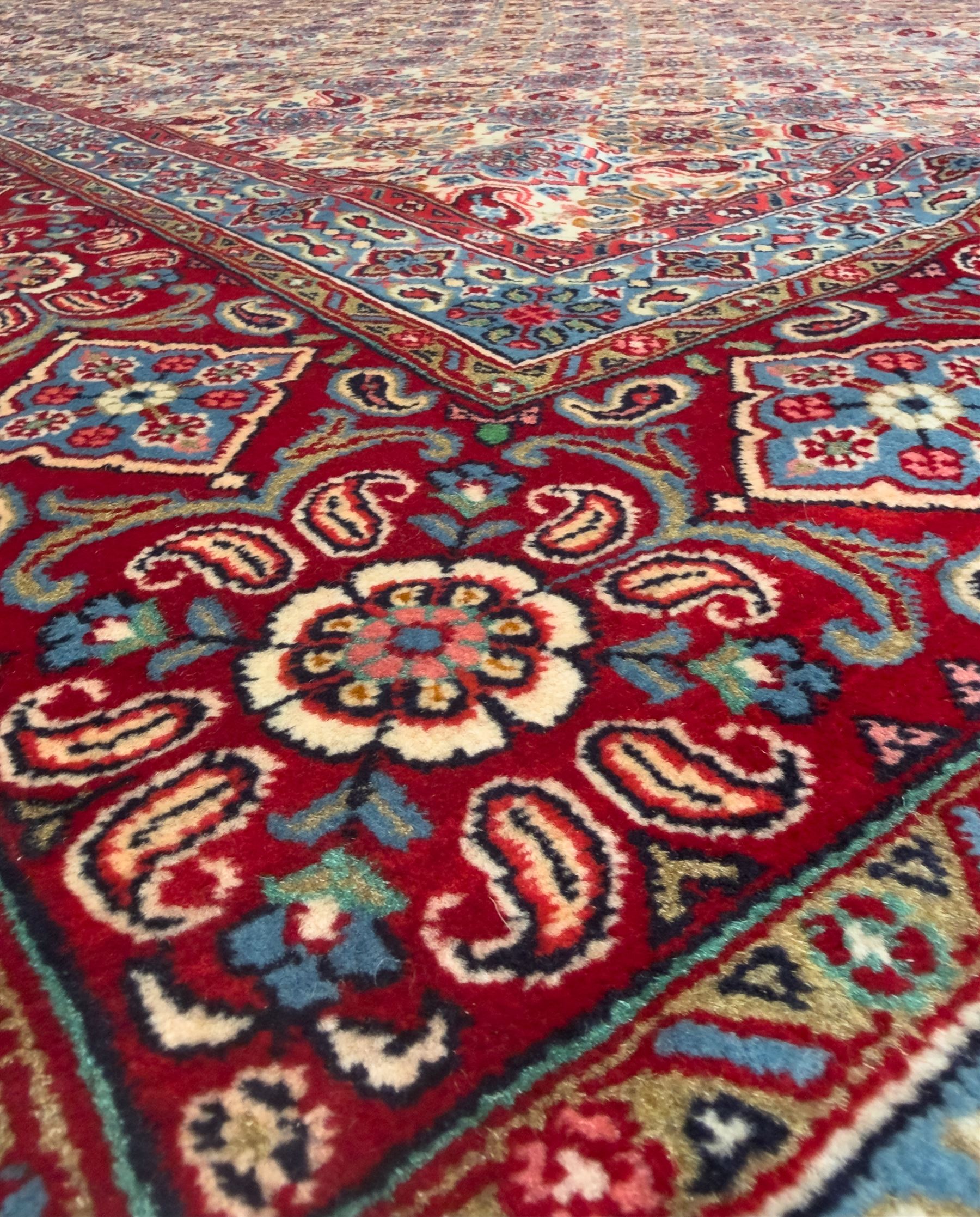 Northwestern Persian Hamadan carpet, hand-knotted, ivory field with an all-over Herati design of rosettes and serrated leaves within multiple borders, madder red with angular vine and rosette motifs, 375cm x 271cm 