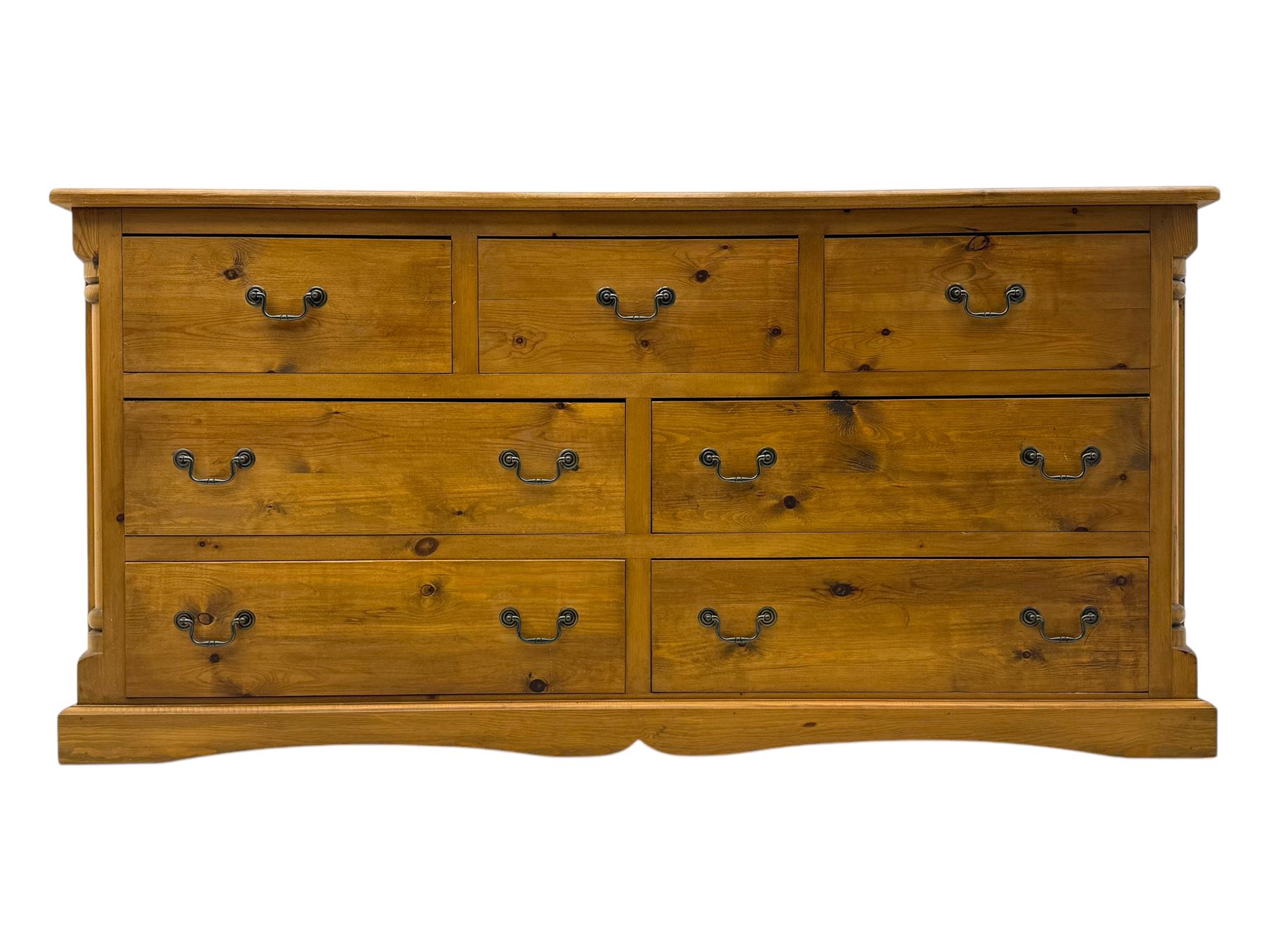 Pine dresser, rectangular top above seven drawers, with two smaller drawers over five larger drawers, all fitted with cast metal handles, raised on a shaped plinth base

