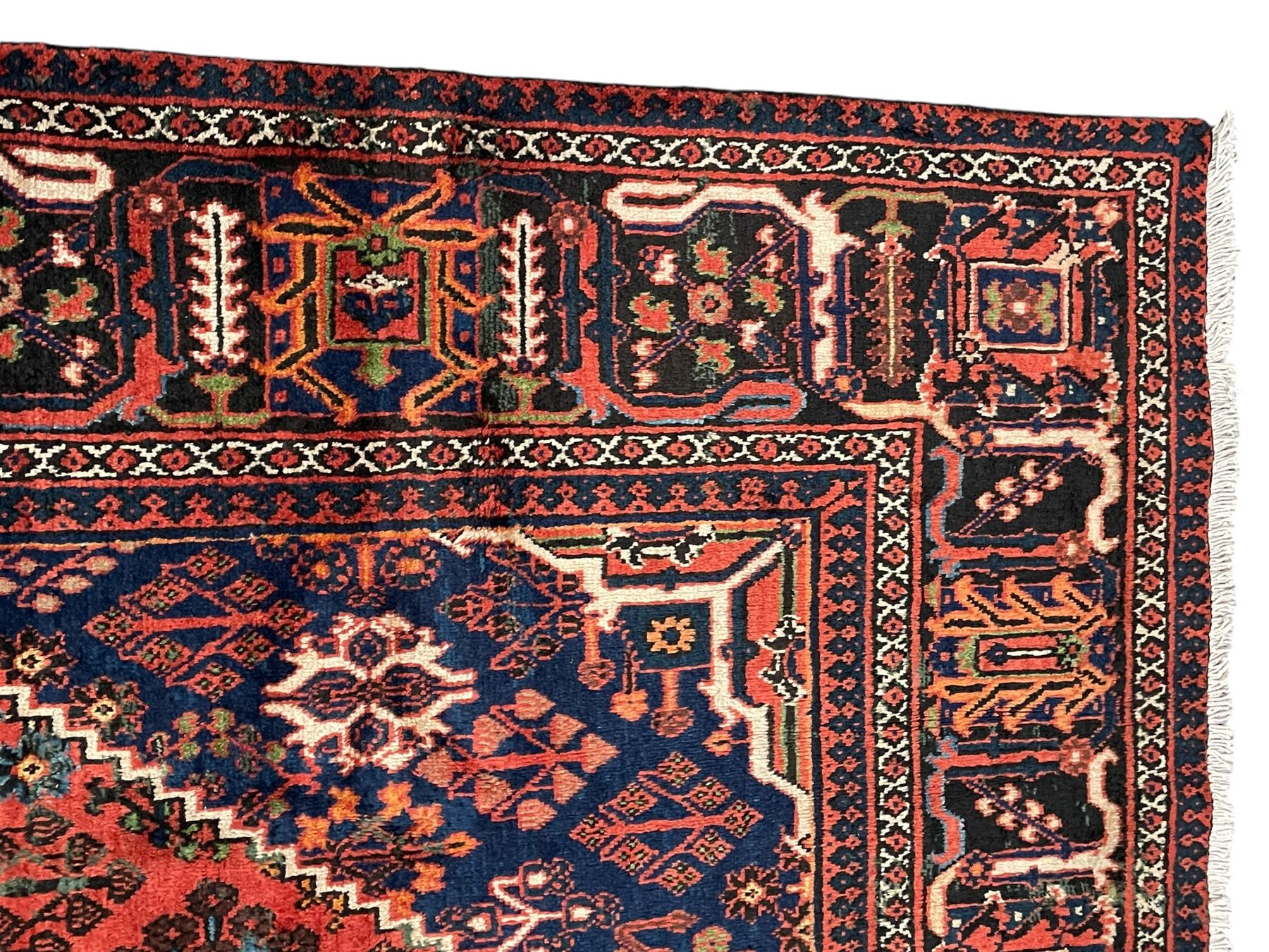 Persian Joshgan red ground rug, the medallion, field and spandrels decorated with clusters of Pitrak and tree of life motifs, the border with repeating design decorated with stylised plant motifs, within guard stripes