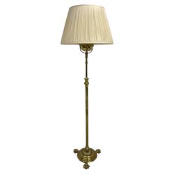 Edwardian brass plated copper standard lamp, telescopic stem on lobe moulded circular base with three projecting paw feet, with cream shade