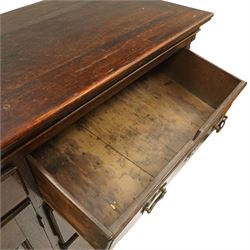 19th century Georgian oak long dresser base, rectangular plank top above a central frieze drawer over a fielded panel cupboard, flanked by three banks with quarter cantered pilasters, brass swan neck handles and escutcheons, raised on shaped bracket feet