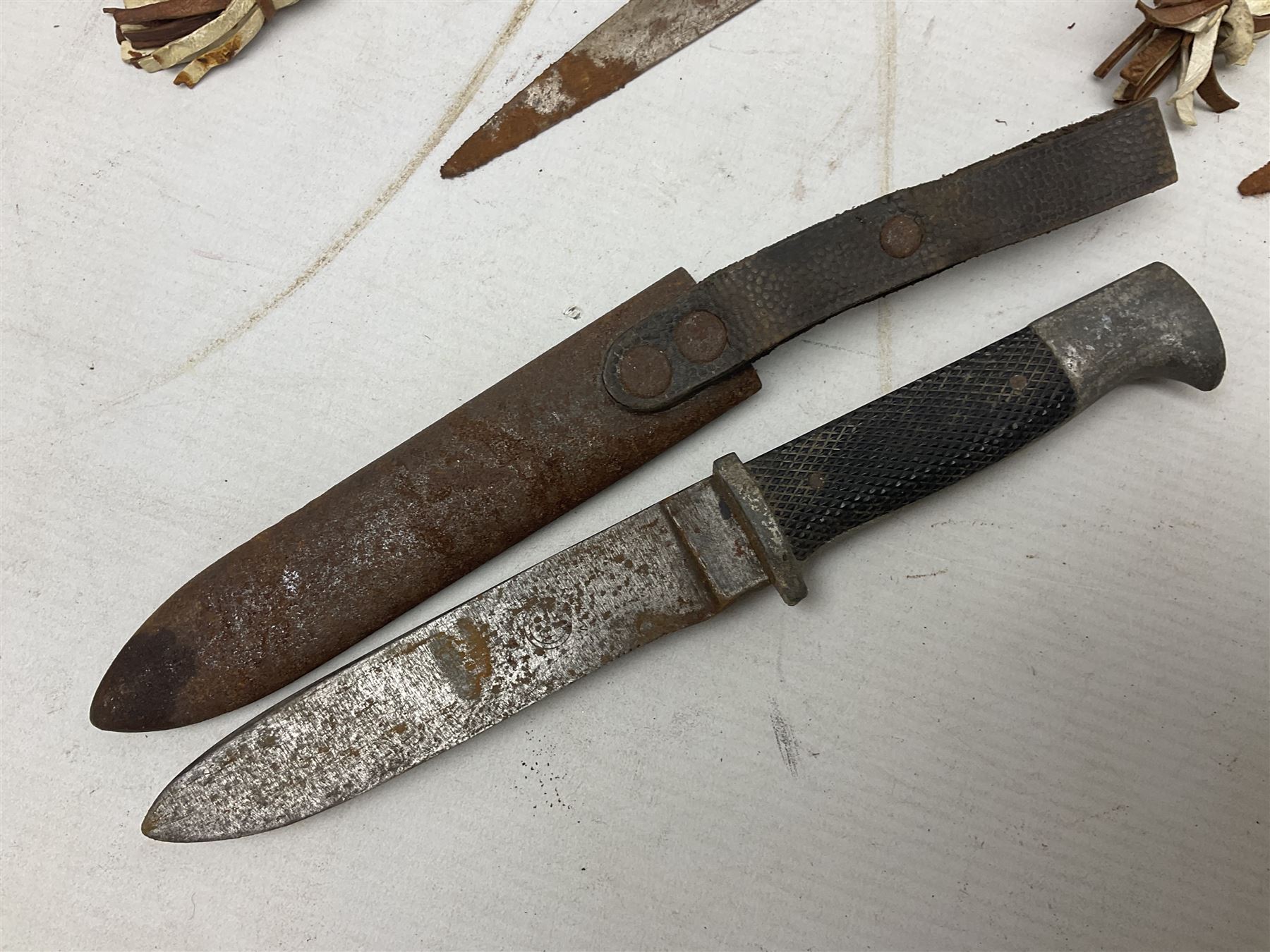 Indian kukri with 29cm curving steel blade and nickel mounted horn grip; in leather covered scabbard with one skinning knife L42cm overall; Hitler Youth knife with scabbard in relic condition; and three African graduated knives each with crudely carved wooden grips and painted leather covered scabbards (5)