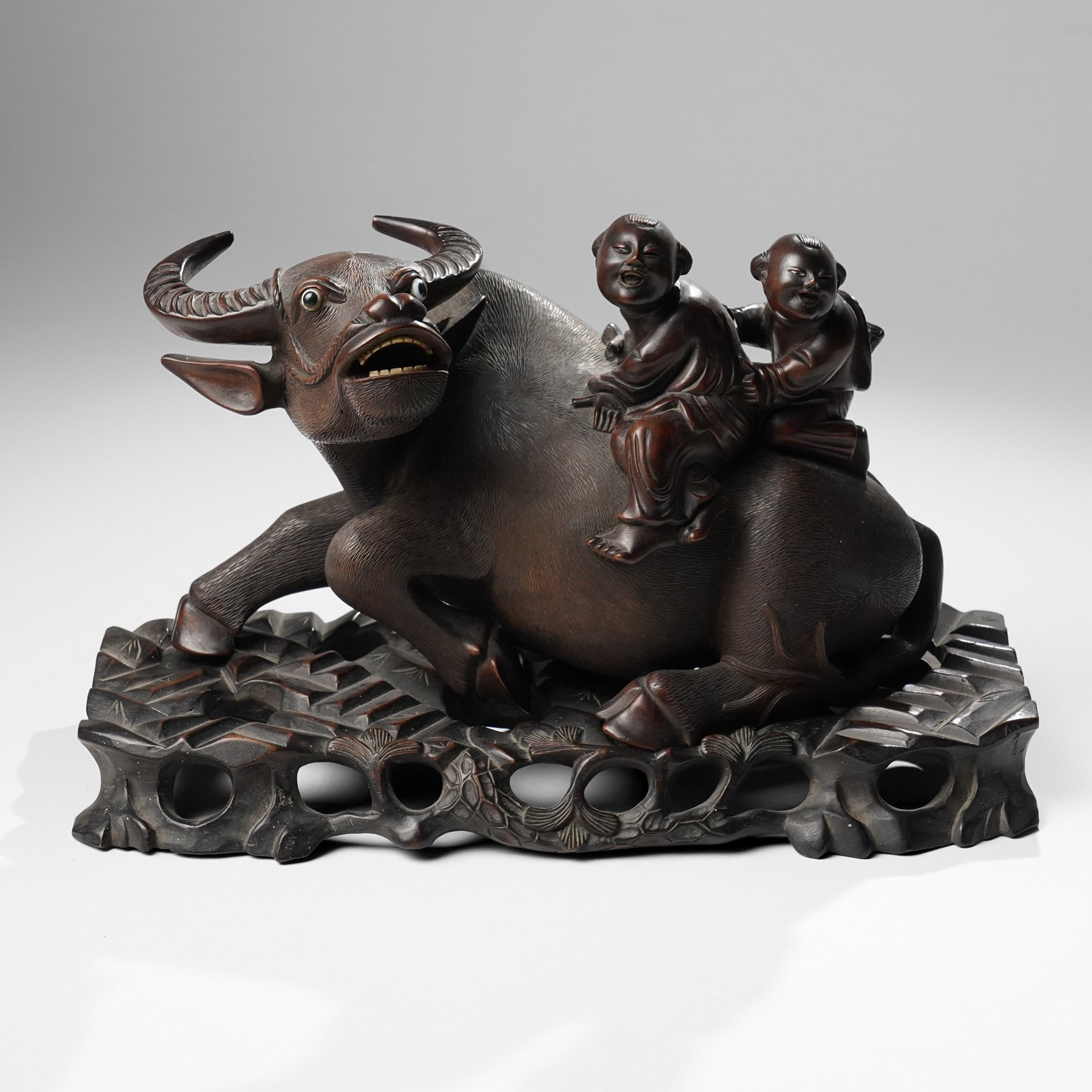 Early 20th century Chinese carved hardwood figural group of two boys on the back of a water buffalo on wooden stand W37cm