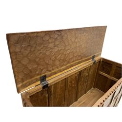 Gnomeman - oak blanket box, all-over adzing, the hinged top over figured and burr panelled front, decorated with carved crenellations and arcade, carved with gnome signature, pierced handles to each end forming the central rail, wrought metal hinges, on stile supports, by Tom Whittaker, Littlebeck, Whitby