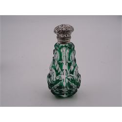Late Victorian green flashed and facet cut scent bottle, of pear shaped form with hinged foliate detailed silver cover, opening to reveal an interior glass stopper, H8cm, unmarked but testing as silver, together with a further late Victorian clear cut glass example, of cylindrical form, also with hinged foliate detailed silver cover, opening to reveal and interior glass stopper, hallmarked M Bros, Birmingham 1899, H7cm, (2)
