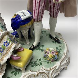 20th century Naples figure group, modelled as a seated female figure playing the lute seated, before a male figure stood holding a sheet of music, each in period dress, upon an oval base with gilt heightened scroll edge, with crowned N mark beneath, H31.5cm L33cm
