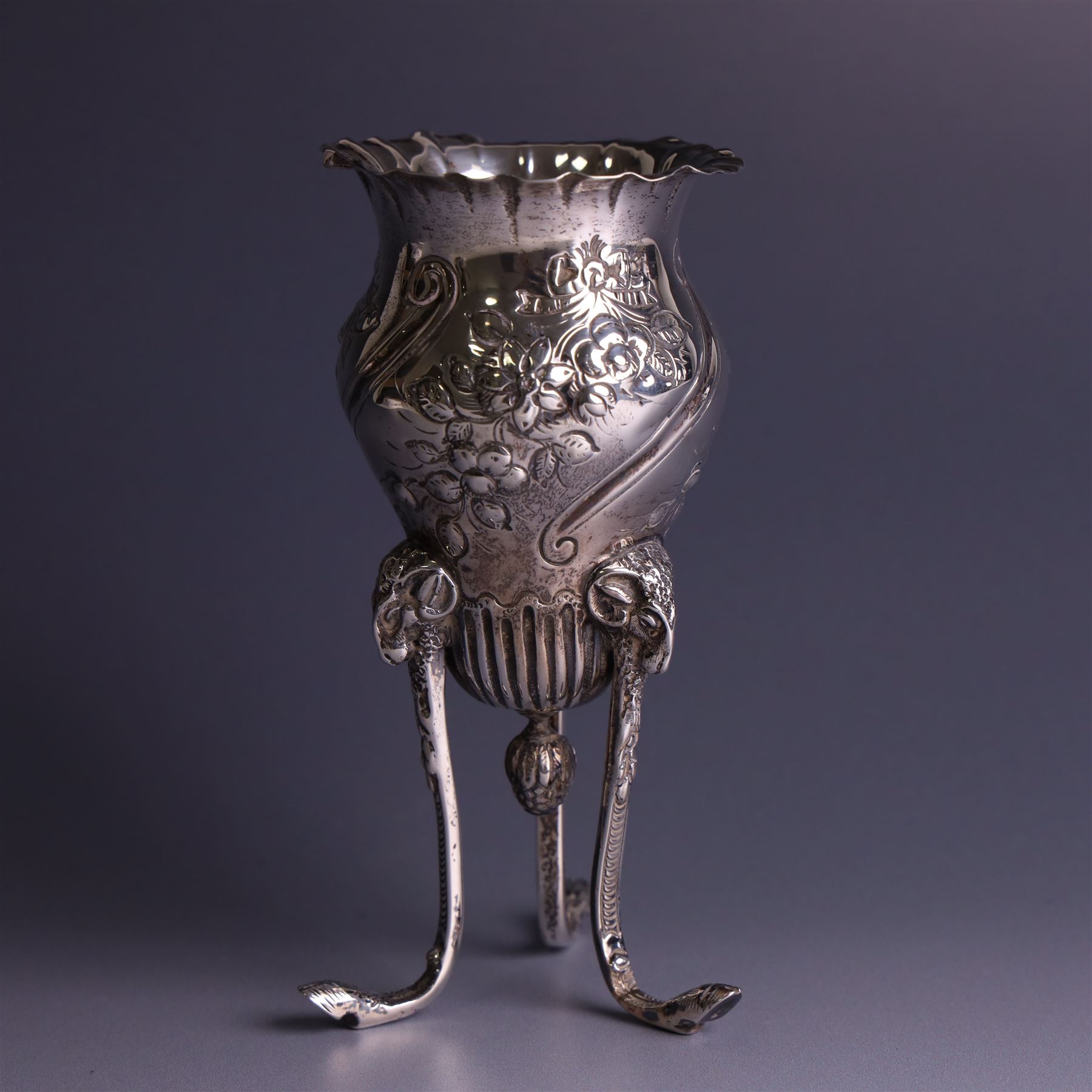 Late Victorian silver vase, of baluster form with fluted rim, the body with embossed floral decoration, upon three tall legs with ramshead mounts, hallmarked William Comyns & Sons, London 1890, H13.5cm