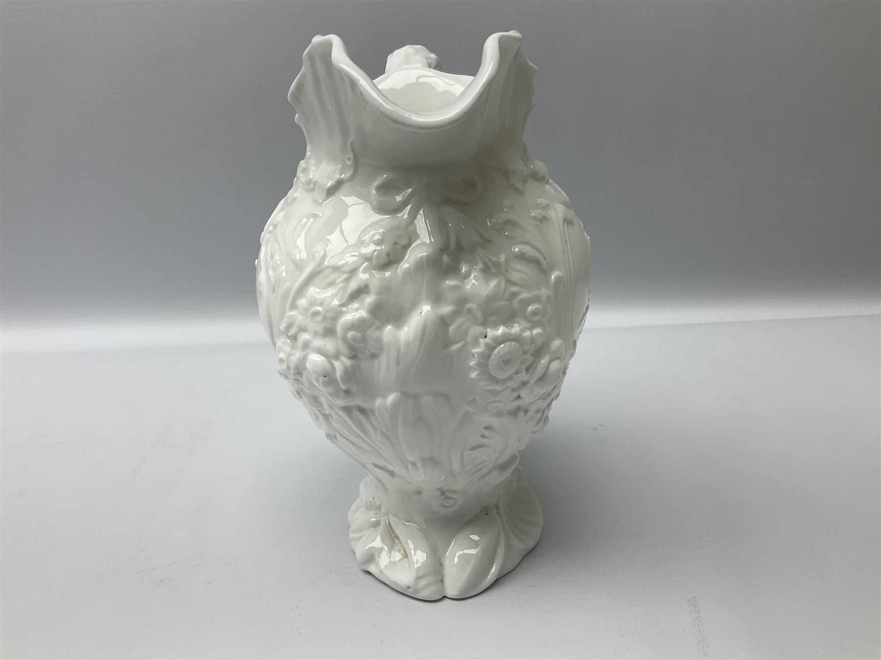 Pair of early/mid 19th century Copeland and Garrett white glazed pitchers, modelled in the Georgian style and moulded with the figures of Venus the Roman Goddess of Love, and Aurora the Roman Goddess of Dawn, within C scroll borders and foliate surround, the naturalistically modelled handle leading to a fruiting vine beneath the rim, upon a spreading base moulded with seashells, with printed green crowned wreath mark beneath, H20cm