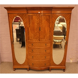 Edwardian triple mahogany wardrobe, projecting cornice above two bow fronted panelled doors with three adjustable shelves, four central graduating drawers, two full height doors with bevel edged oval mirrors, interior with hanging rails, hooks and drawer units, spade supports, W195cm, H219cm, D59cm  