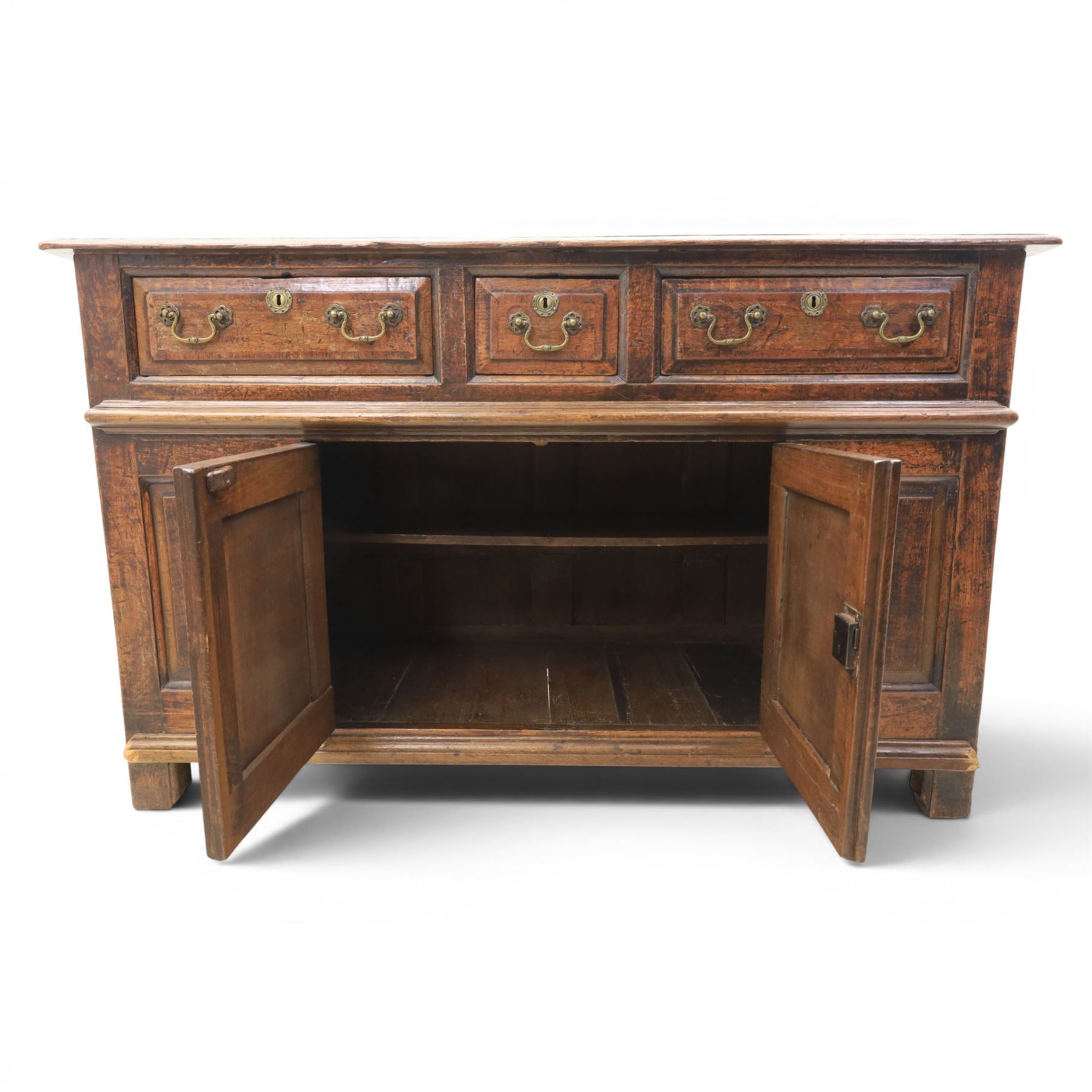 George III oak dresser base, rectangular top with moulded edge, three fielded panelled drawers with brass swan neck handles, over four fielded panelled front with the central two cupboard doors, raised on stile supports