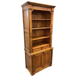 French cherry wood bookcase on cupboard, projecting moulded cornice over three shelves and two small drawers, the cupboard enclosed by two panelled doors flanked by fluted uprights