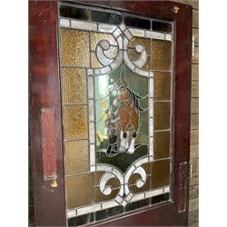 Two early to mid 20th century timber doors, set with lead framed stained glass panels depicting agricultural worker and horse
