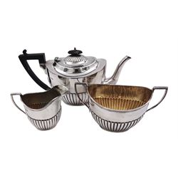 Early 20th century silver three piece tea service, comprising teapot, twin handled sucrier, and milk jug, each of oval part fluted form, the teapot with ebonised handle and finial, hallmarked Sheffield 1918, maker's mark WHM